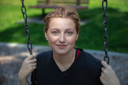 young woman sitting in a swing at the park playing outside happy enjoyment leisure