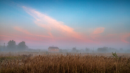 Early morning scenery in field. Foggy morning in the field. Yellow sunrise with fog in summer.
