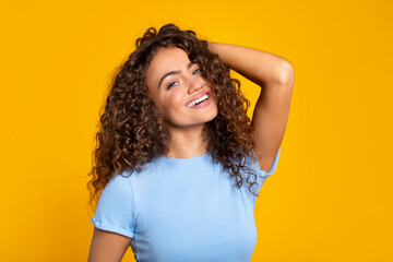 Delighted young woman smiling brightly on yellow