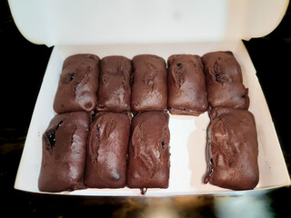 a group of several chocolate brownies in a white box on a black table