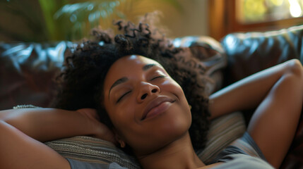 A young happy black woman lying back on a sofa relaxing