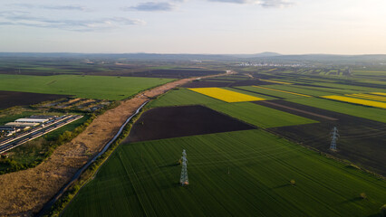 drone view of cultivated fields river, agricultural farm and factory in the distance in early spring at sunset