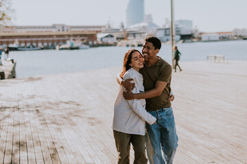 Radiant couple embraces on a sunny Barcelona boardwalk, exuding happiness and love