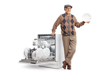 Senior man leaning on a dishwasher and holding a plate