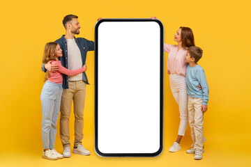 Family looking at big smartphone screen on yellow background