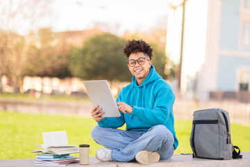 Happy student using tablet outside, studying at park