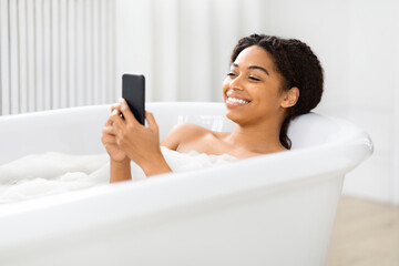 Woman using smartphone in the tub at home