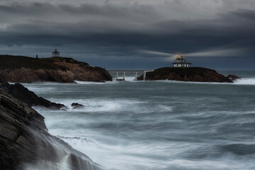 Pancha Island Lighthouse in Ribadeo, Lugo, Galicia, on a sunset with many clouds and a dramatic sky...