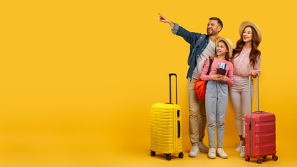 Family ready for vacation pointing away on yellow background