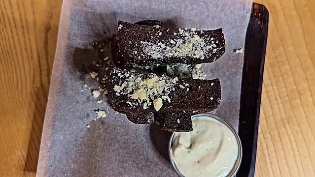A tray of brownies with a white sauce on the side. The brownies are covered in a white powdery substance