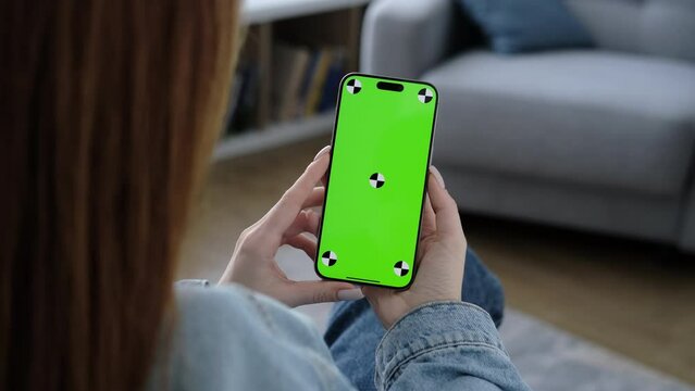 Woman using smartphone vertical green screen. Female holding in hand portable gadget. Tracking markers. Indoors. Browsing social network, news. Mock-up for tracking. Watching content video blog 4K