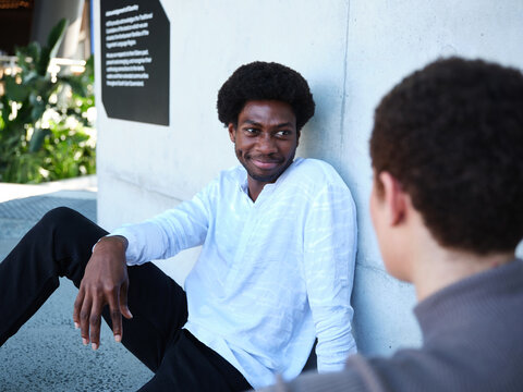 Man and woman sitting against a concrete wall having a conversation