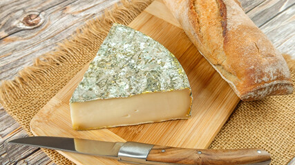 fromage français : Saint-Nectaire fermier, en gros plan, sur une planche à découper	
