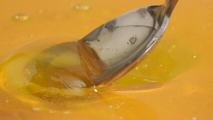 Healthy organic honey. Sweet fresh golden honey on the yellow background with honey spoon scooping...