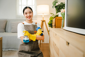 Young female housekeeper holds cleaning supplies in the house