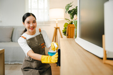 Young female housekeeper cleaning And wipe down the table with a microfiber cloth in the living...