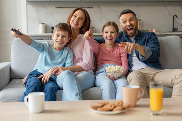 Family cheering while watching TV together at home
