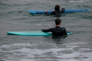 Naklejka premium Playa de Málaga, surf en la cosota del sol, surferos entrando en el agua, tabla de surf, olas, vacaciones y deporte, feflejo en la orilla del mar