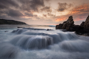 Sunset of warm colors and dramatic sky with clouds on Azkorri or Gorrondatxe beach in Getxo,...
