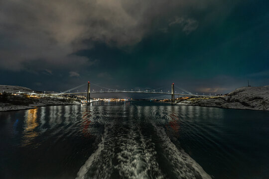 Blick vom Meer aus auf die Br&uuml;cke bei Rorvik (Norwegen) , die beleuchtete Stadt spiegelt sich im Wasser