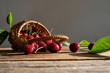 ripe cherries in a small basket close-up on a wooden table