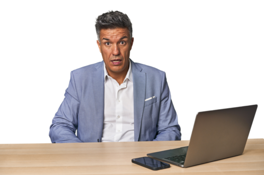 Elegant businessman at desk with laptop shouting very angry, rage concept, frustrated.