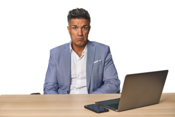 Elegant businessman at desk with laptop sad, serious face, feeling miserable and displeased.