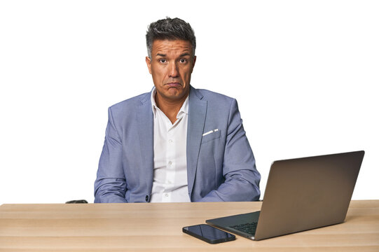 Elegant businessman at desk with laptop sad, serious face, feeling miserable and displeased.