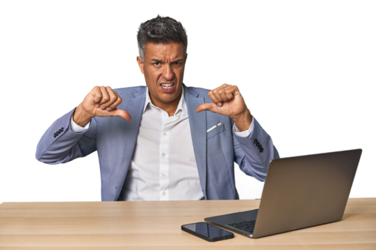 Elegant businessman at desk with laptop showing thumb down and expressing dislike.