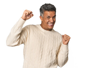 Middle-aged Latino man celebrating a special day, jumps and raise arms with energy.