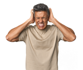 Middle-aged Latino man covering ears with hands trying not to hear too loud sound.