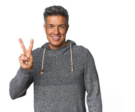 Middle-aged Latino man showing victory sign and smiling broadly.