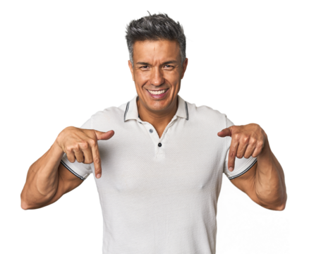 Middle-aged Latino man points down with fingers, positive feeling.