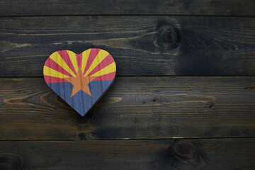 wooden heart with national flag of arizona state on the wooden background.