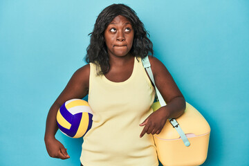 Young curvy woman with cooler and ball confused, feels doubtful and unsure.