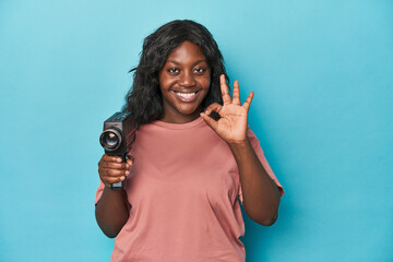 Curvy lady with vintage film camera cheerful and confident showing ok gesture.
