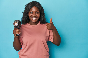 Curvy lady with vintage film camera smiling and raising thumb up