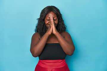 Young african american curvy woman holding hands in pray near mouth, feels confident.