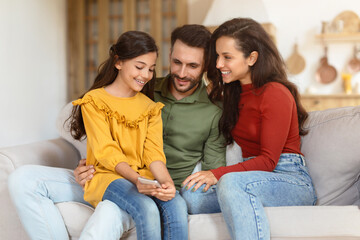 Smiling family using smartphone together at home