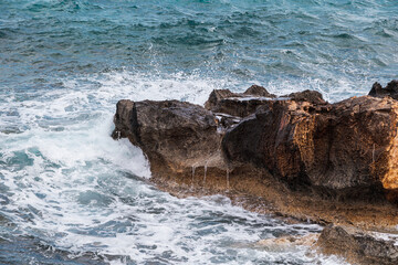 Ocean waves crash against coastal rocks, shaping the natural landscape