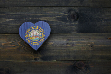 wooden heart with national flag of new hampshire state on the wooden background.