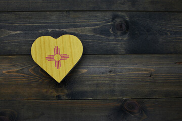 wooden heart with national flag of new mexico state on the wooden background.