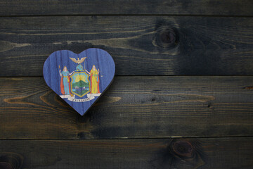 wooden heart with national flag of new york state on the wooden background.