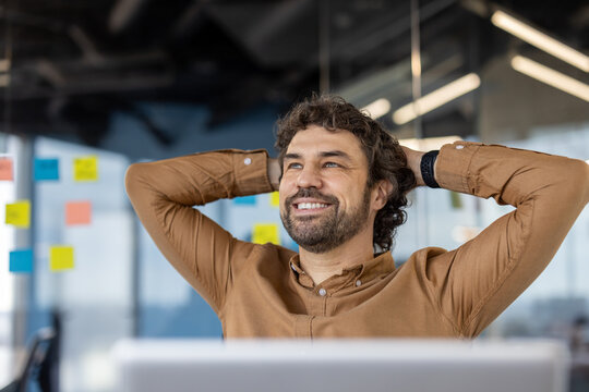 A mature Hispanic man exhibits a content smile, resting at his workplace with a confident posture.