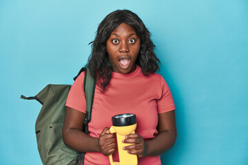 Ready for adventure, curvy woman with backpack on blue backdrop - obrazy, fototapety, plakaty