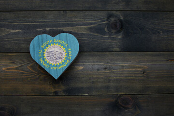 wooden heart with national flag of south dakota state on the wooden background.