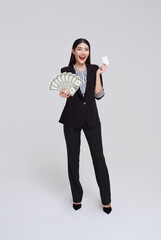 Happy asian business woman showing, presenting credit card and money dollars, smiling and laughing, isolated on white studio background.