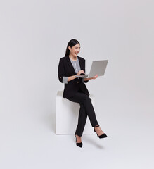 Young business woman asian happy smiling. While her using laptop sitting on white chair isolated on white background.