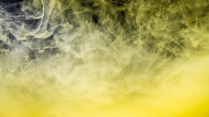 Obraz na płótnie Canvas clouds of yellow smoke on a black background, clouds of paint in water, aquarium, abstract background, texture