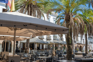 Sombrillas con mesas de hostelería y restaurantes en la plaza Grande de Zafra, ajardinada con...